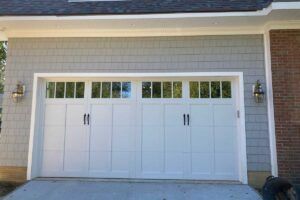 White double garage doors on a brick house with small window panes above.