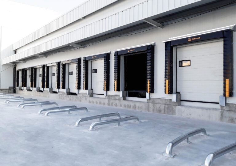 Loading dock with multiple warehouse bays and metal ramps in front of closed and open doors