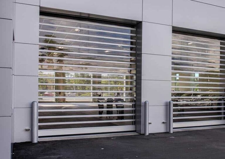 Modern building facade with two large metallic roll-up shutters closed over windows.