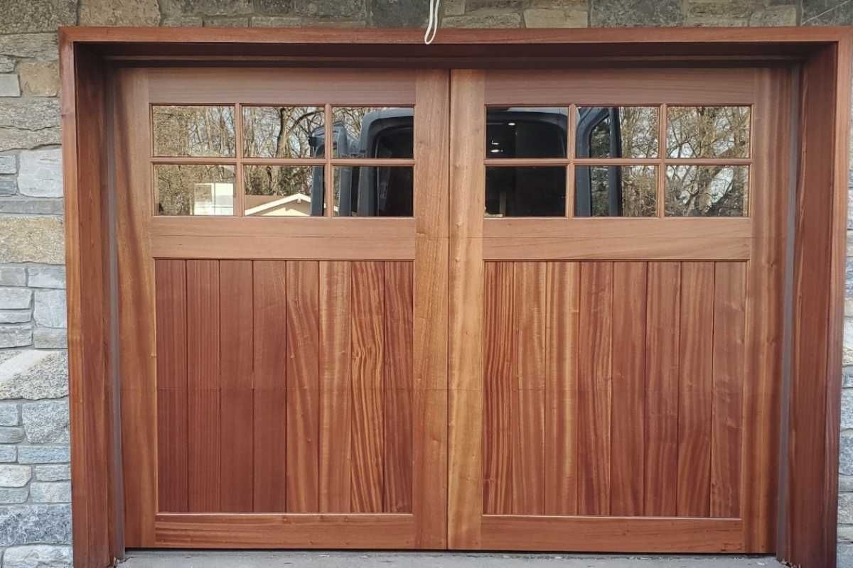 Wooden garage door with small window panes set into a stone wall