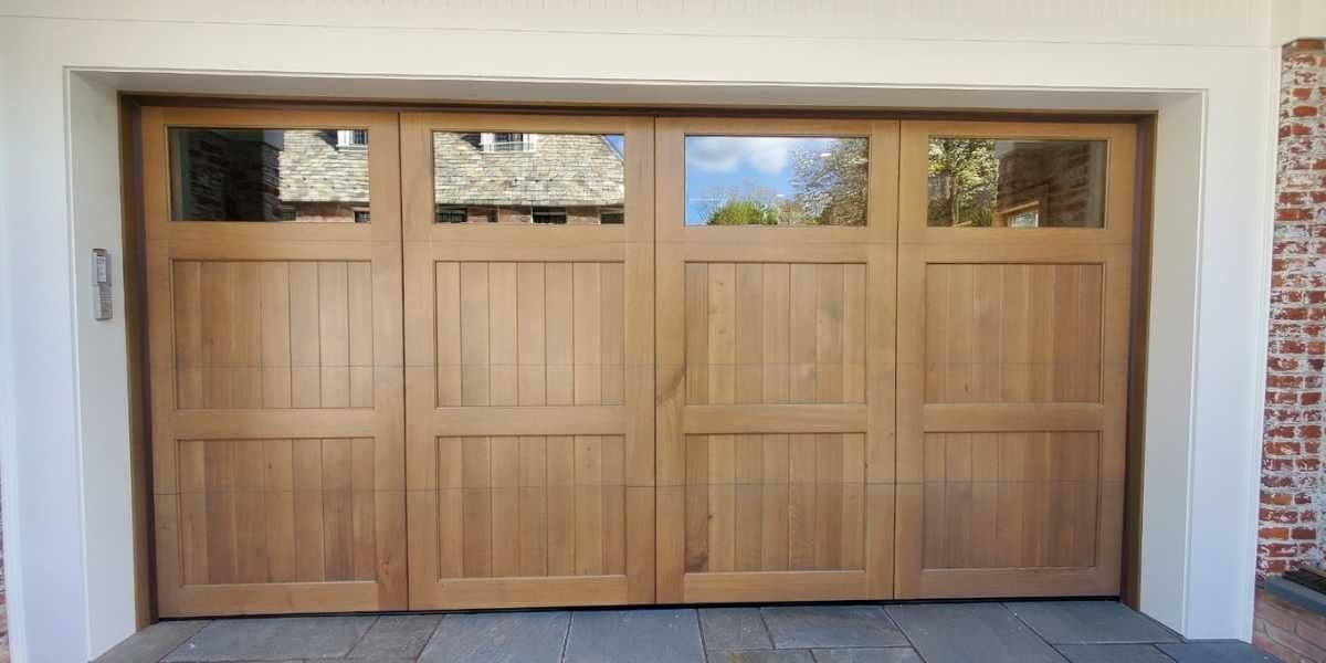 Wooden four-car garage door with small windows, set in a white stucco wall