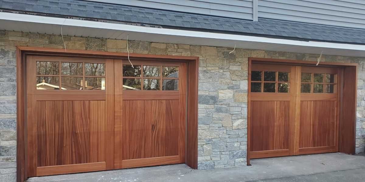 Two wooden garage doors set in a stone exterior wall under a gray roofline.