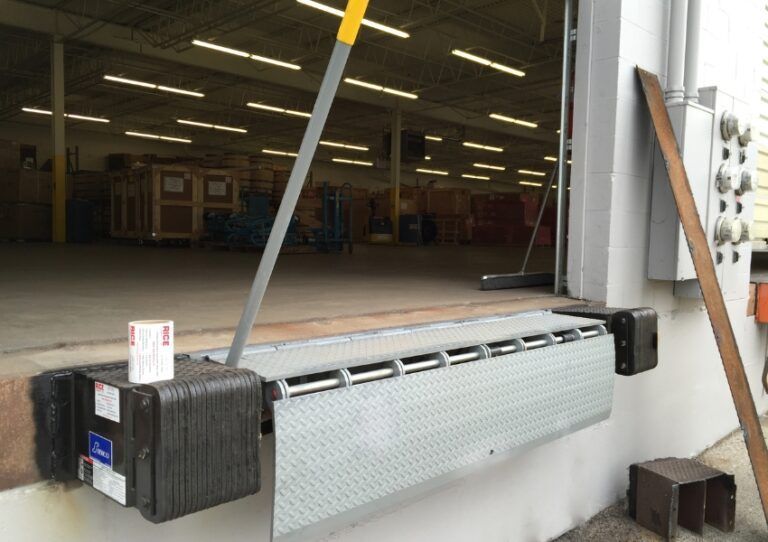Loading dock with a large open bay door, a ramp, and a metal barrier across the entrance