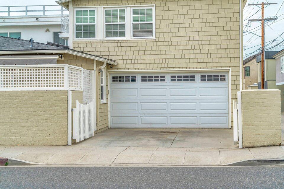 Residential garage with white doors and beige stucco exterior viewed from the street