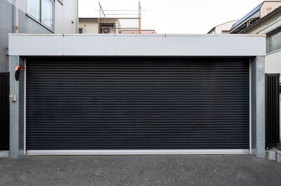 Modern house facade with a closed black roller garage door and concrete driveway