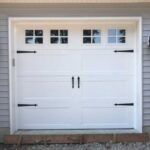 White garage door with windows and black handles on a house exterior