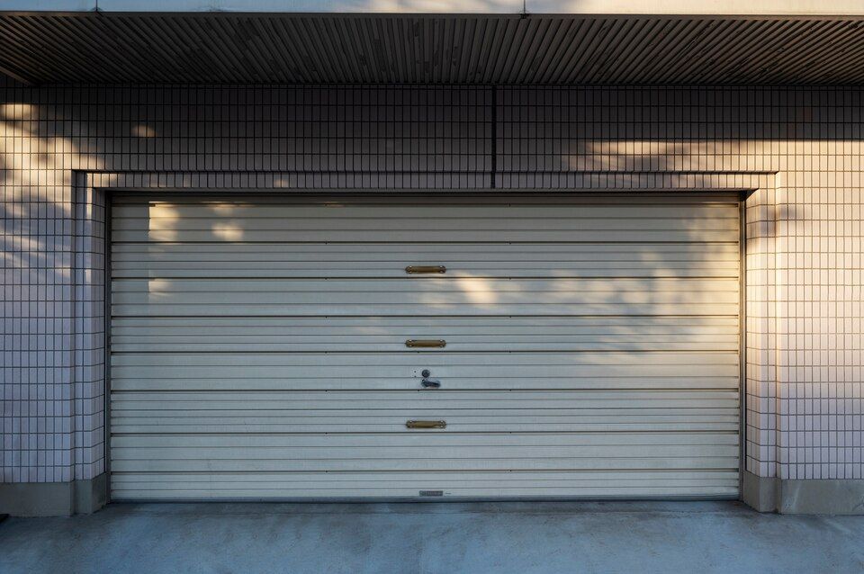 Closed white roll-up garage door under a tiled awning, framed by white brick walls.