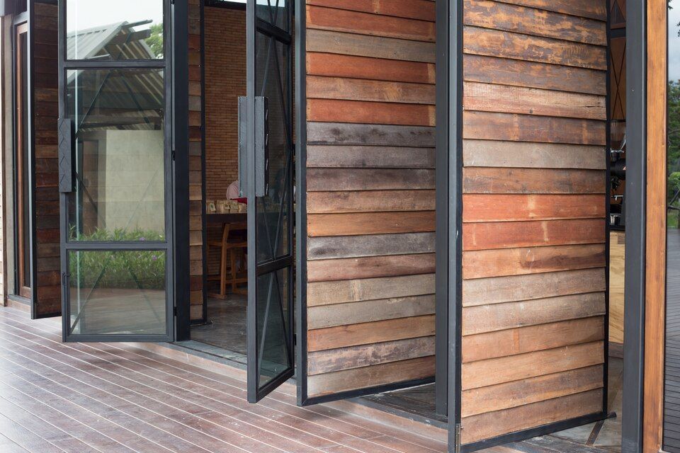 Wooden building exterior with open glass doors and horizontal wood siding on a deck.