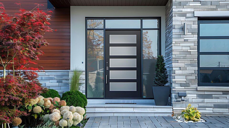 Modern front door with frosted glass panels, stone exterior, and landscaped entryway with potted plants