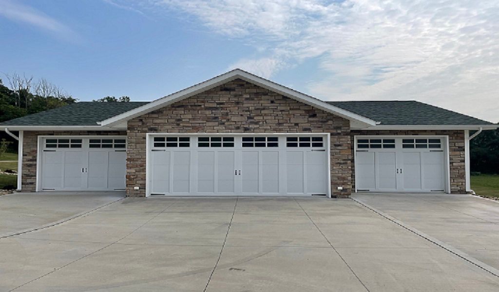 Single-story brick house with three white garage doors and a wide concrete driveway