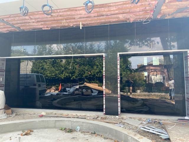 Glass storefront with dark reflective windows and a wood-paneled awning above an unfinished entrance.