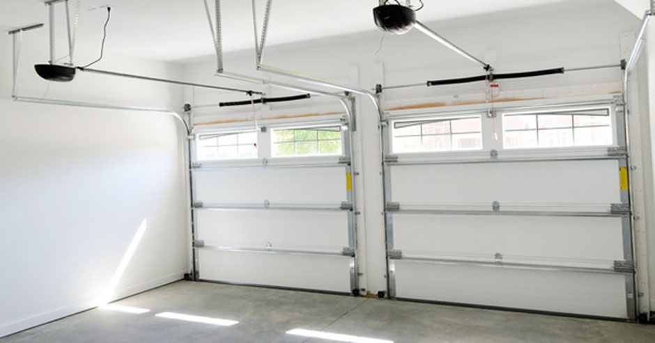 Empty white garage with two overhead doors and a ceiling-mounted opener