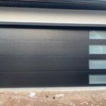 Dark roller garage door with four small frosted windows on the right side.