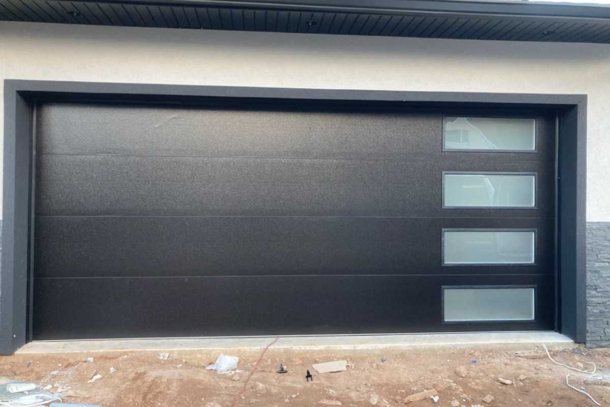 Modern black garage door with three narrow frosted windows on the right.