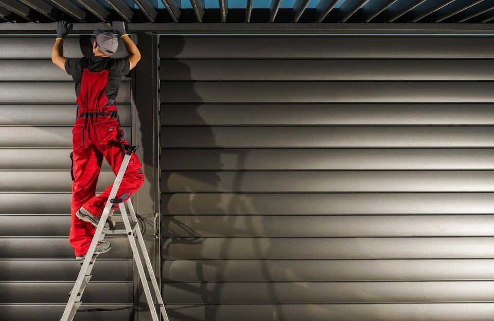 Worker on a ladder repairing a metal shutter door