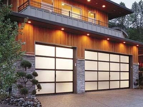 Modern two-story house with frosted glass garage doors and warm exterior lighting at dusk