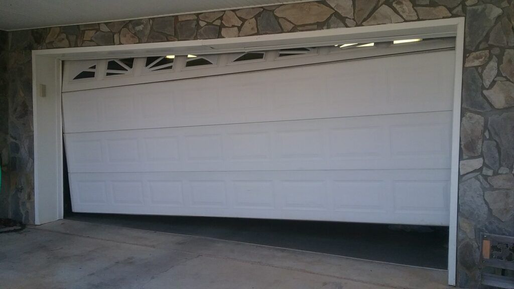 White double garage door on a stone exterior house, closed over a driveway.