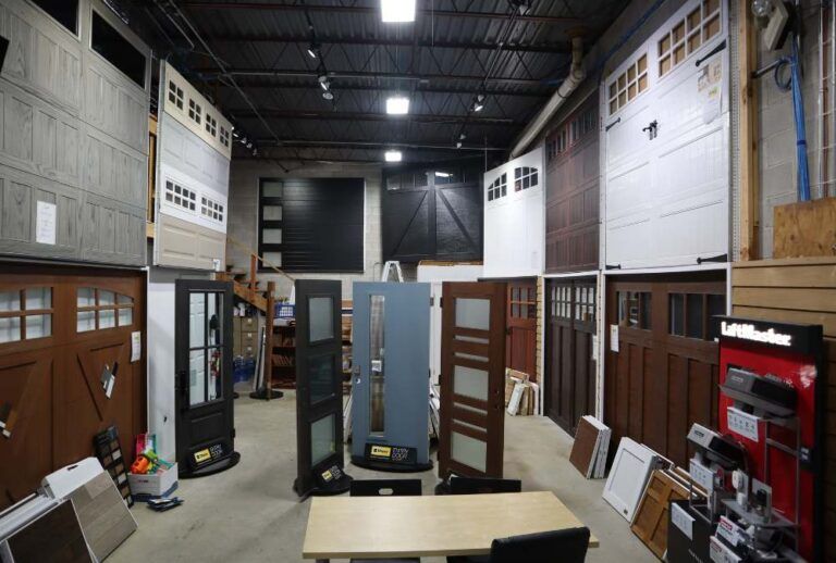 Indoor showroom with display doors, windows, and large architectural panels under bright ceiling lights