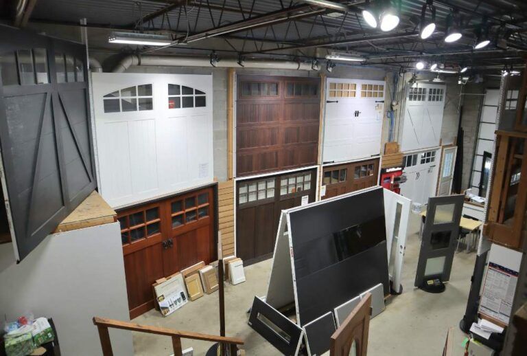 Interior of a warehouse-like showroom with stacked doors, windows, and building materials under bright ceiling lights