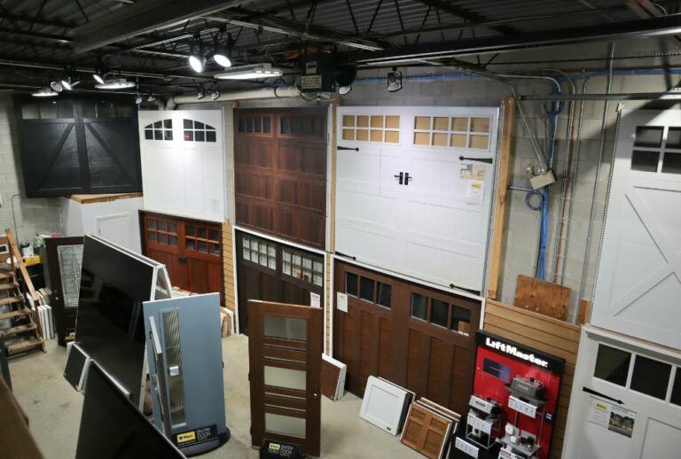 Workshop interior with rows of garage doors, wood panels, and stacked materials under overhead lights