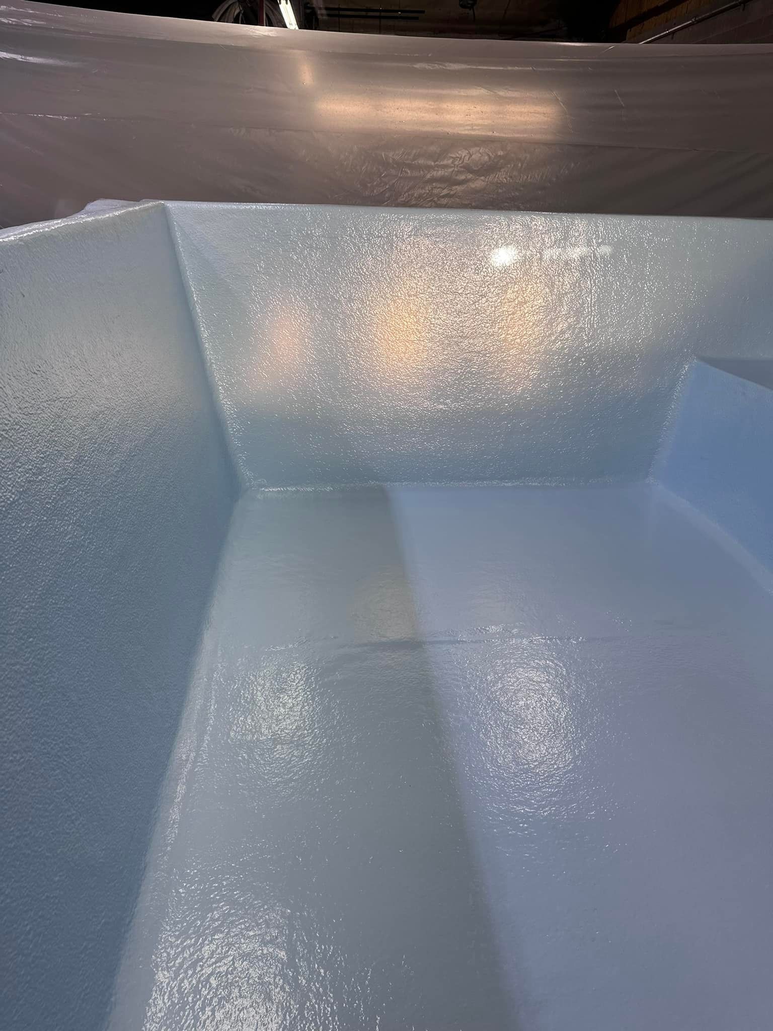 Inside view of a light blue rectangular container with textured walls and a shiny, reflective surface.