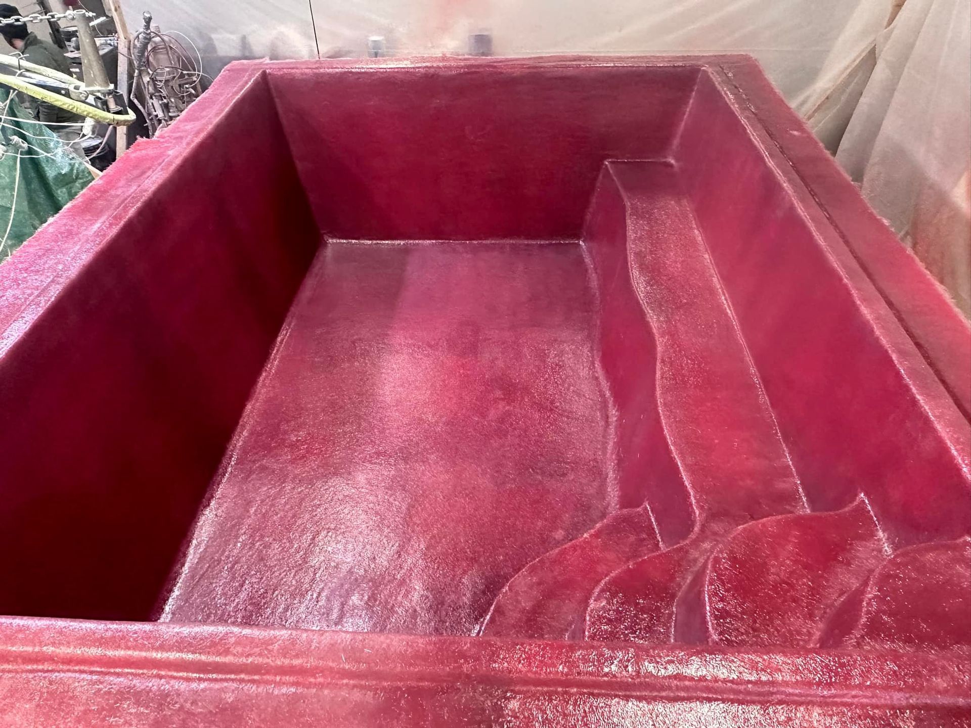 Red rectangular fiberglass pool with steps built in.