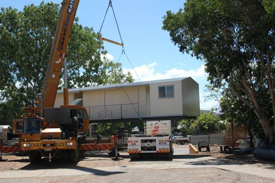 A Large Yellow Crane is Lifting a Building — Downright Carpentry in Ryan, QLD