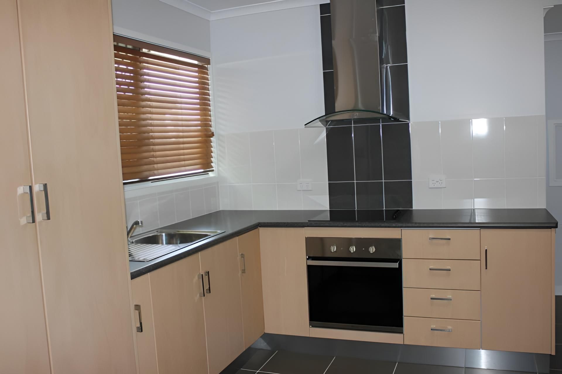 A Kitchen With Stainless Steel Appliances and Wooden Cabinets — Downright Carpentry in Mornington, QLD