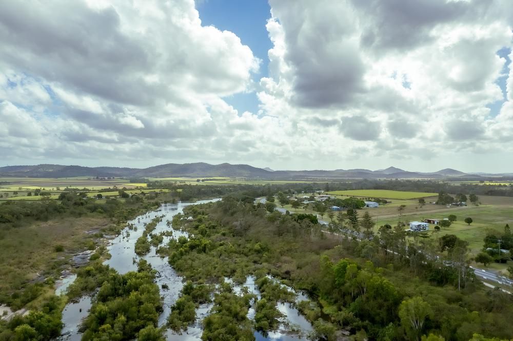 An Aerial View of a River Surrounded by Trees on a Cloudy Day — Downright Carpentry in Pioneer, QLD