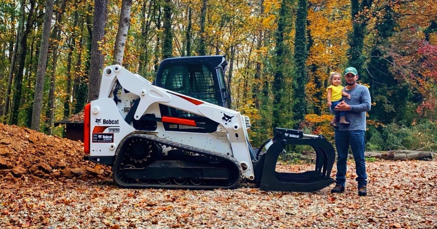 Bobcat machine clearing debris in a wooded area for professional land clearance services.