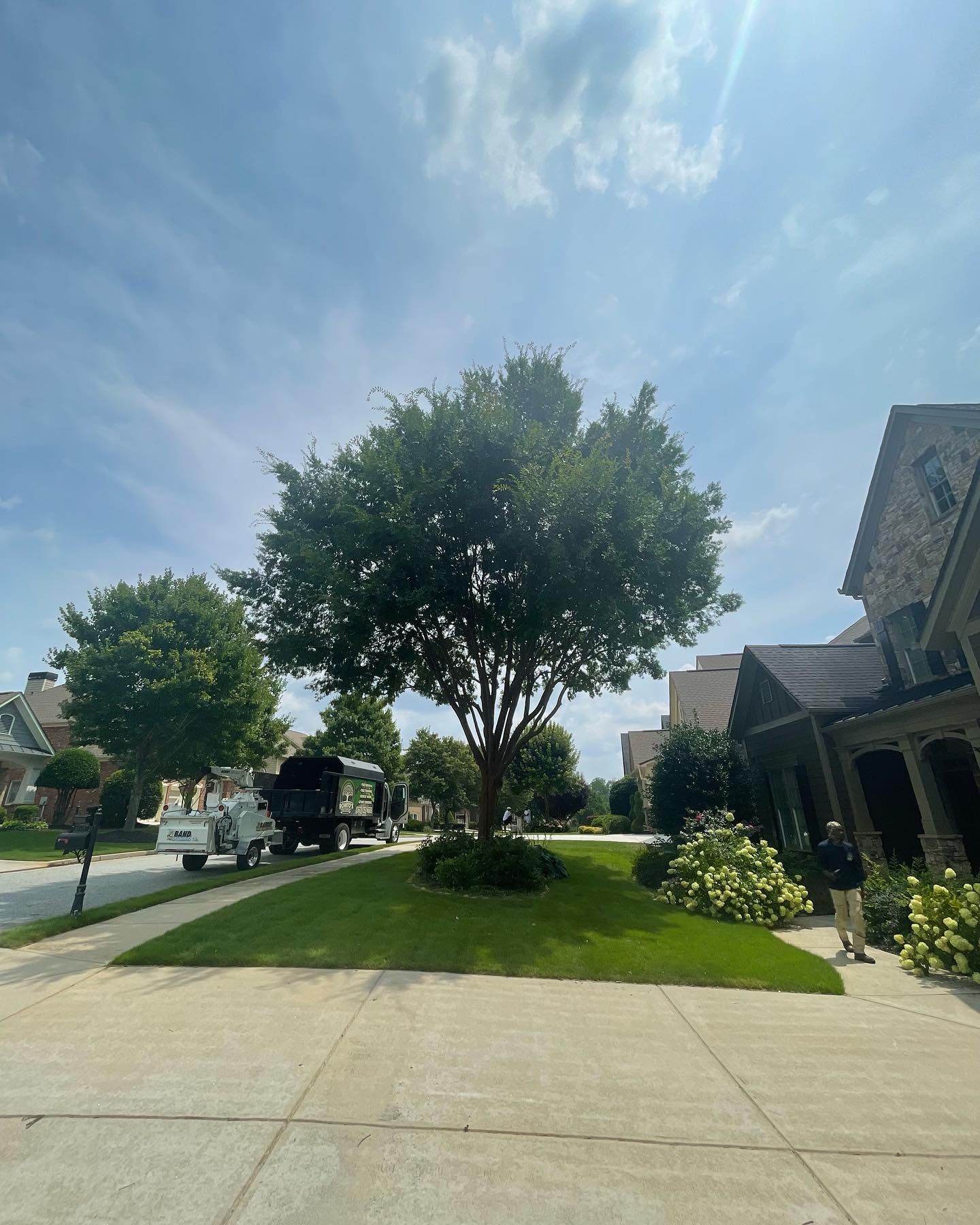 Tree service truck and wood chipper parked on a residential street, ready for professional tree trimming and removal.