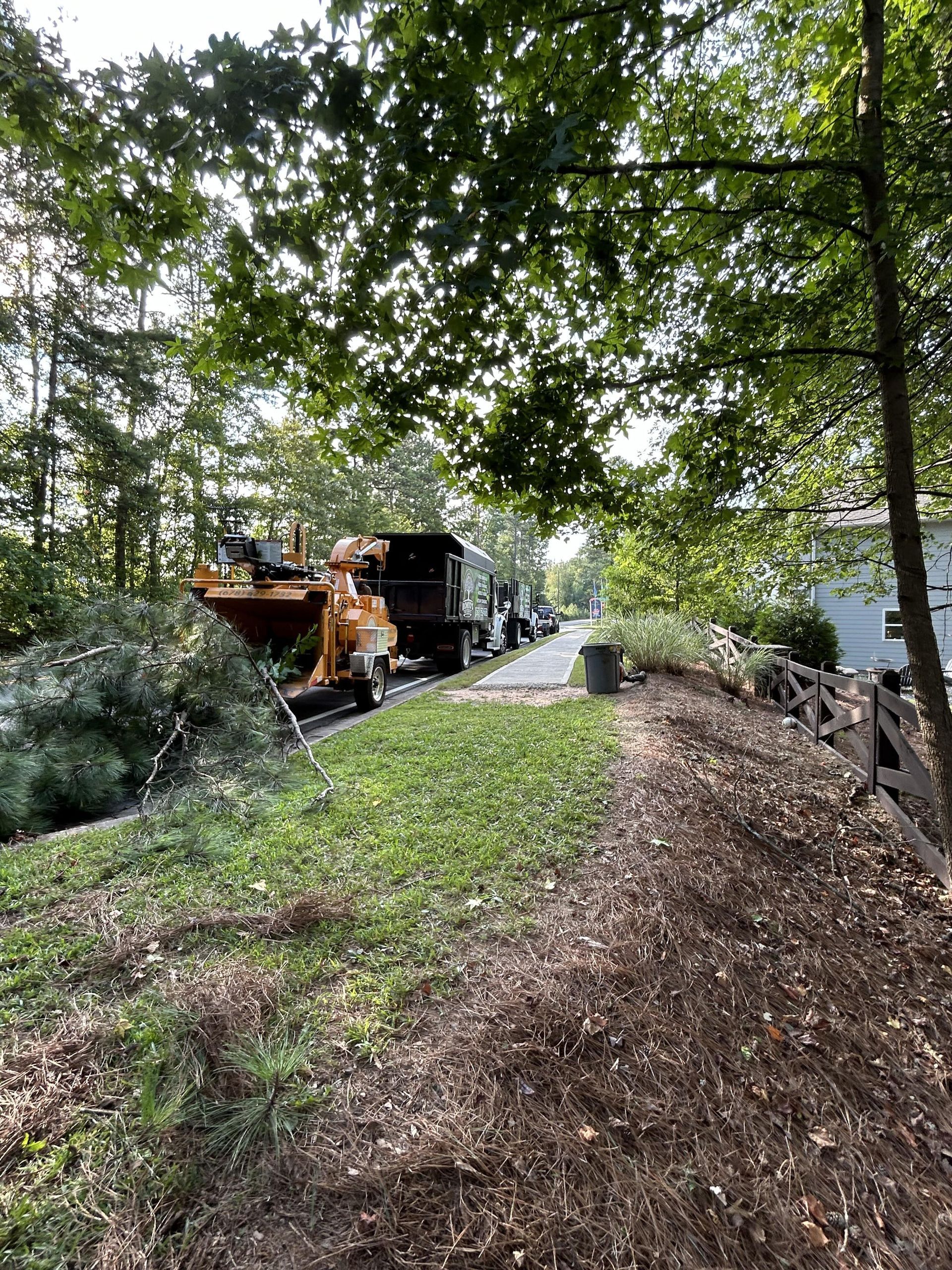 A tree chipper is sitting on the side of a road next to a house.