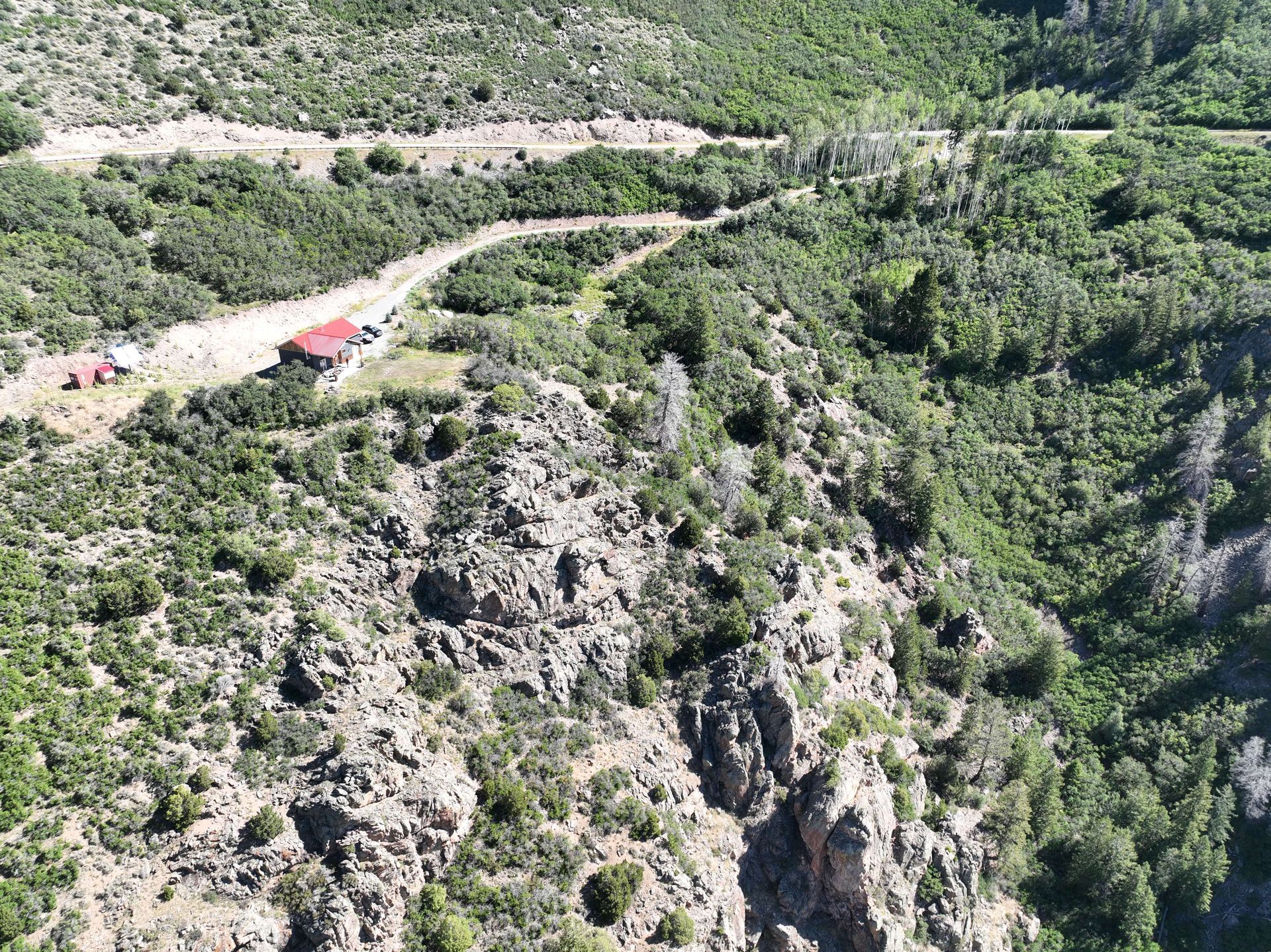 An aerial view of a mountain covered in trees and a road. Maven Construction, Montrose, CO