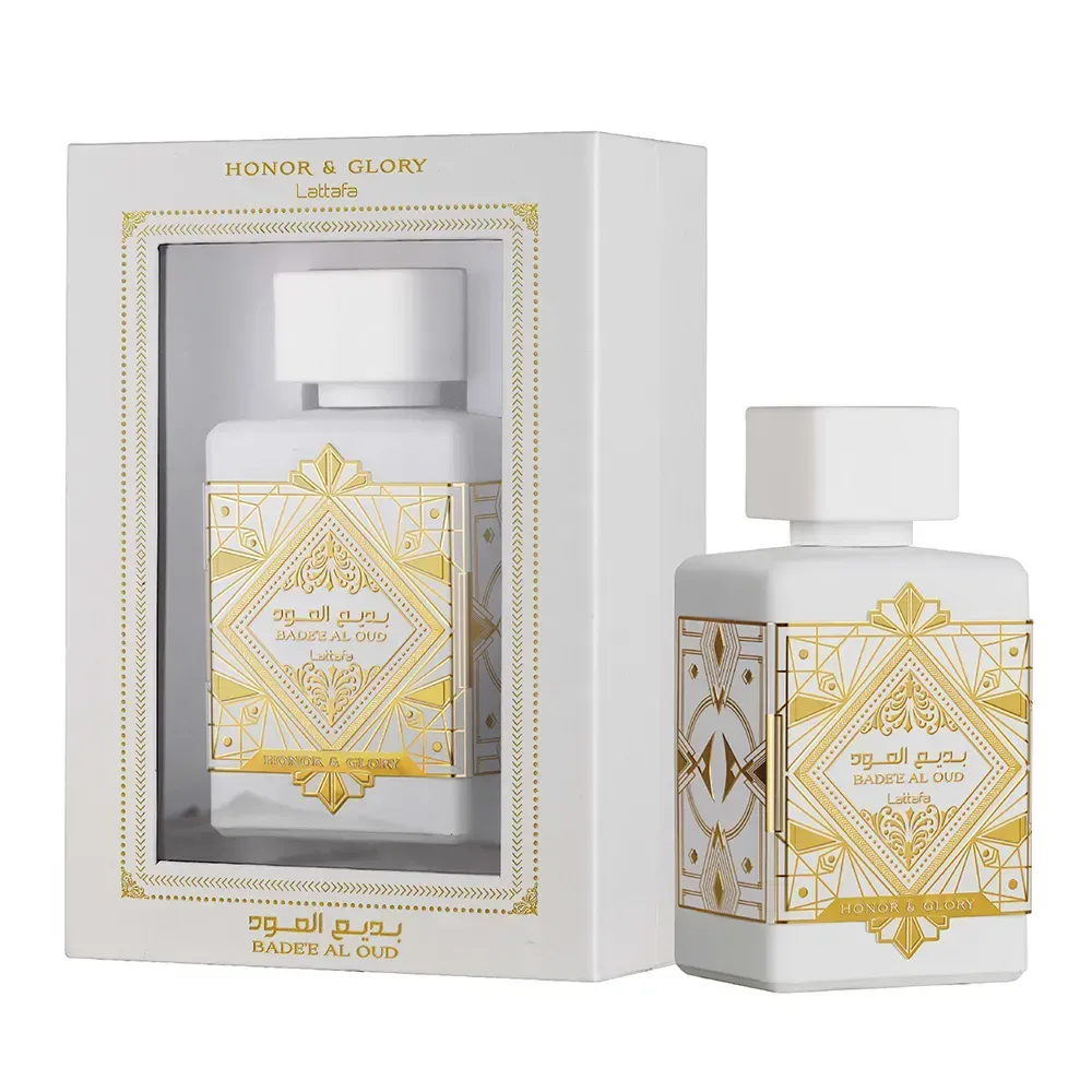 Frasco y caja de perfume blancos y dorados con un diseño ornamentado de estilo árabe sobre un fondo blanco.