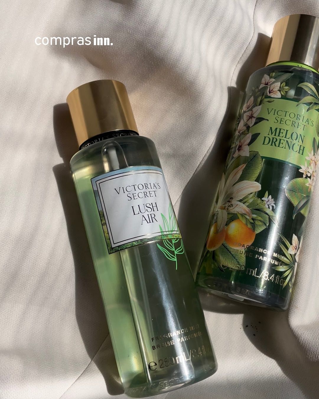 Dos botellas de fragancias Victoria's Secret están sobre una cama.