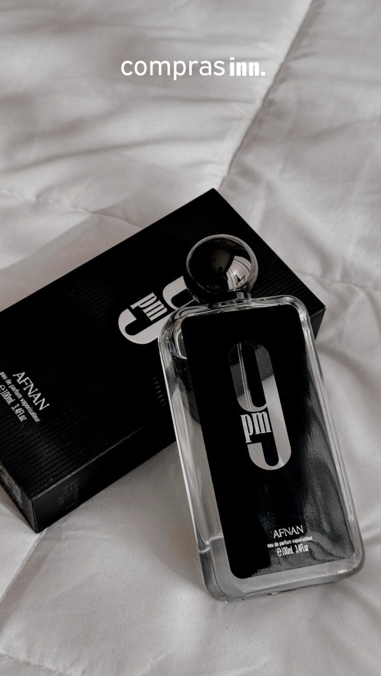 Un frasco de perfume está sobre una cama al lado de una caja.