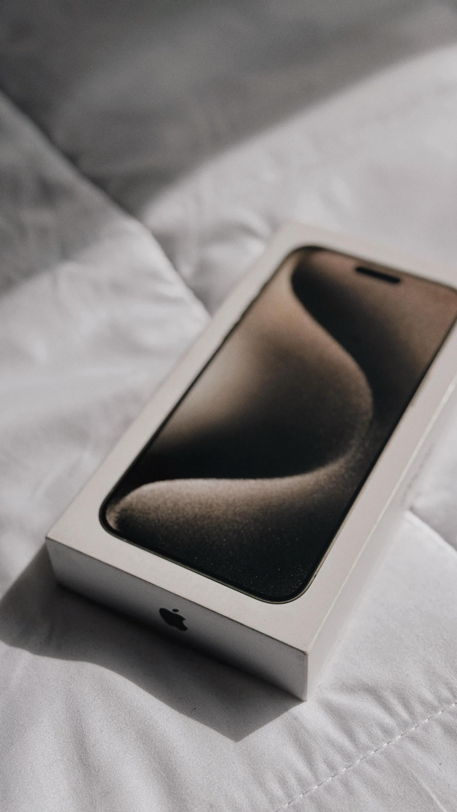 Un teléfono celular en una caja está sobre una cama.