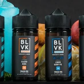 Dos botellas de líquido para cigarrillo electrónico BLVK, una con sabor a rosquillas glaseadas y otra con sabor a tarta de limón y frutos rojos, sobre un fondo oscuro.
