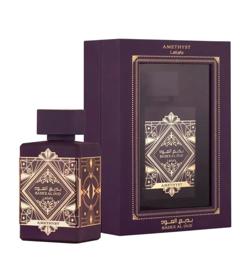 Frasco de perfume morado y caja a juego con diseño dorado de estilo árabe sobre fondo blanco.
