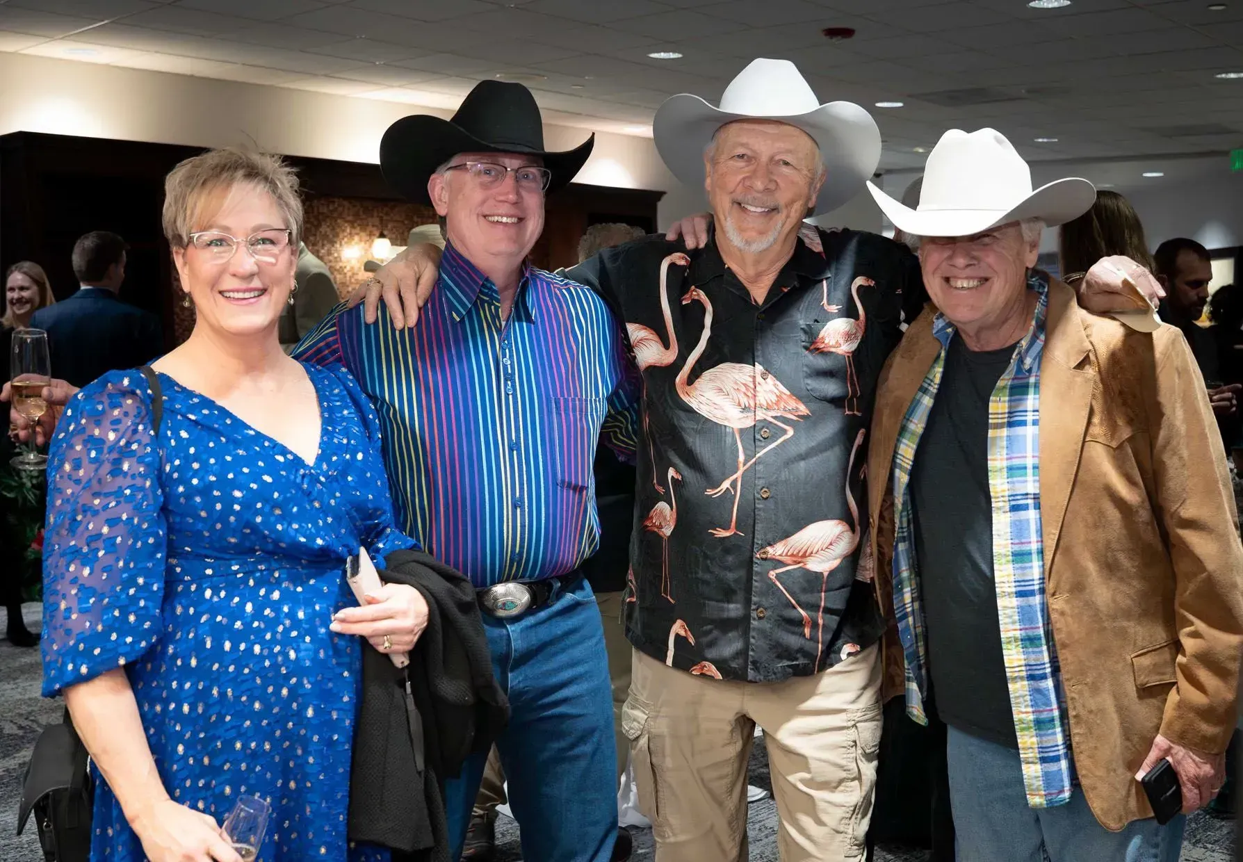 Four people in cowboy hats and Western wear pose for a photo at an event.