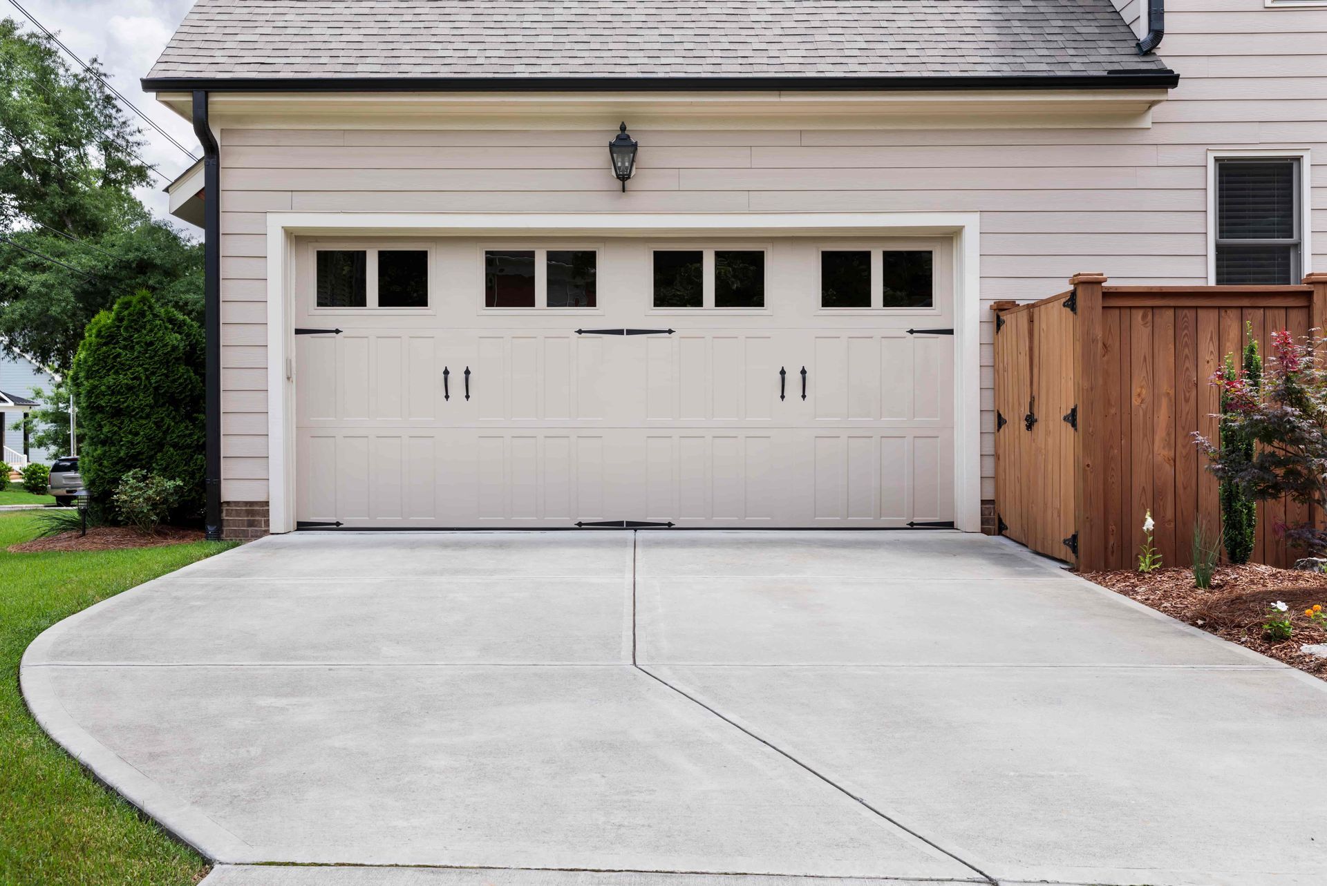 Suburban house with a white double garage door and a wide concrete driveway