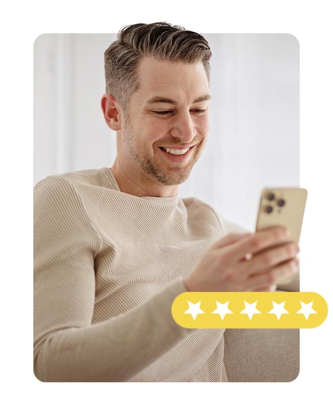 A man is sitting on a couch looking at his cell phone.