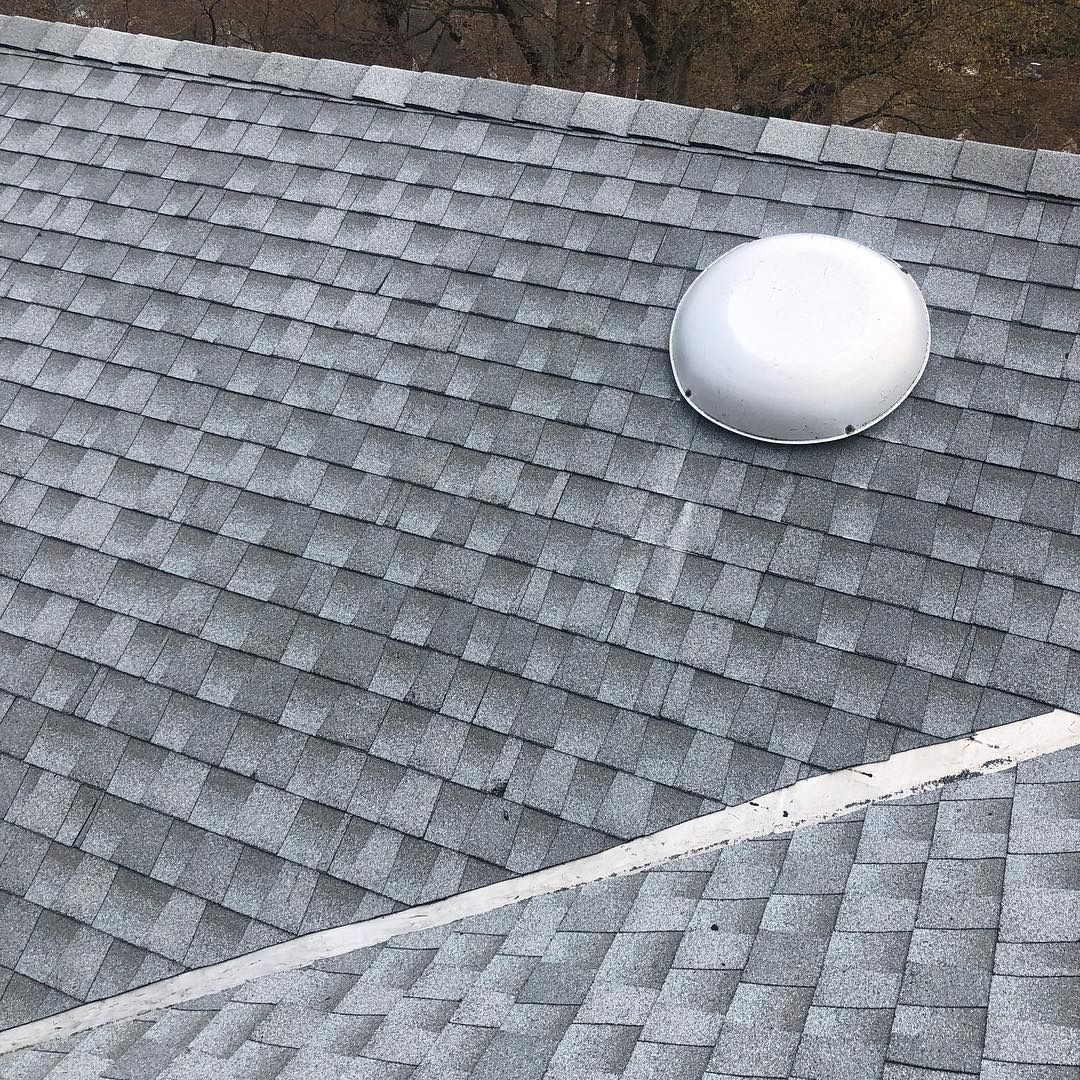 Gray shingled roof with a white dome vent near the top right.