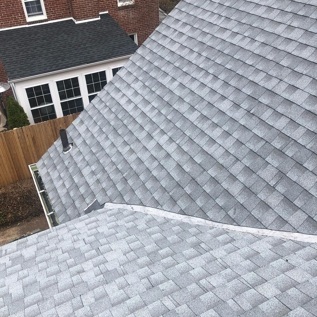 Gray shingled roof with neighboring houses and a wooden fence visible below