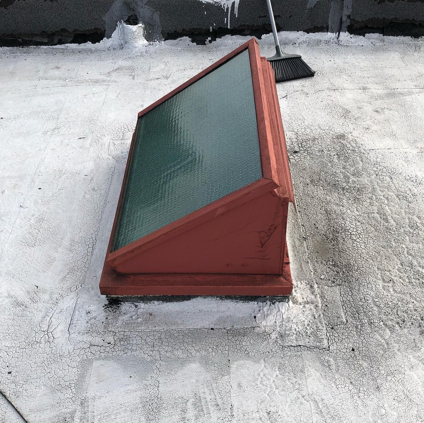 Red-framed rooftop skylight on a snowy, gray roof.