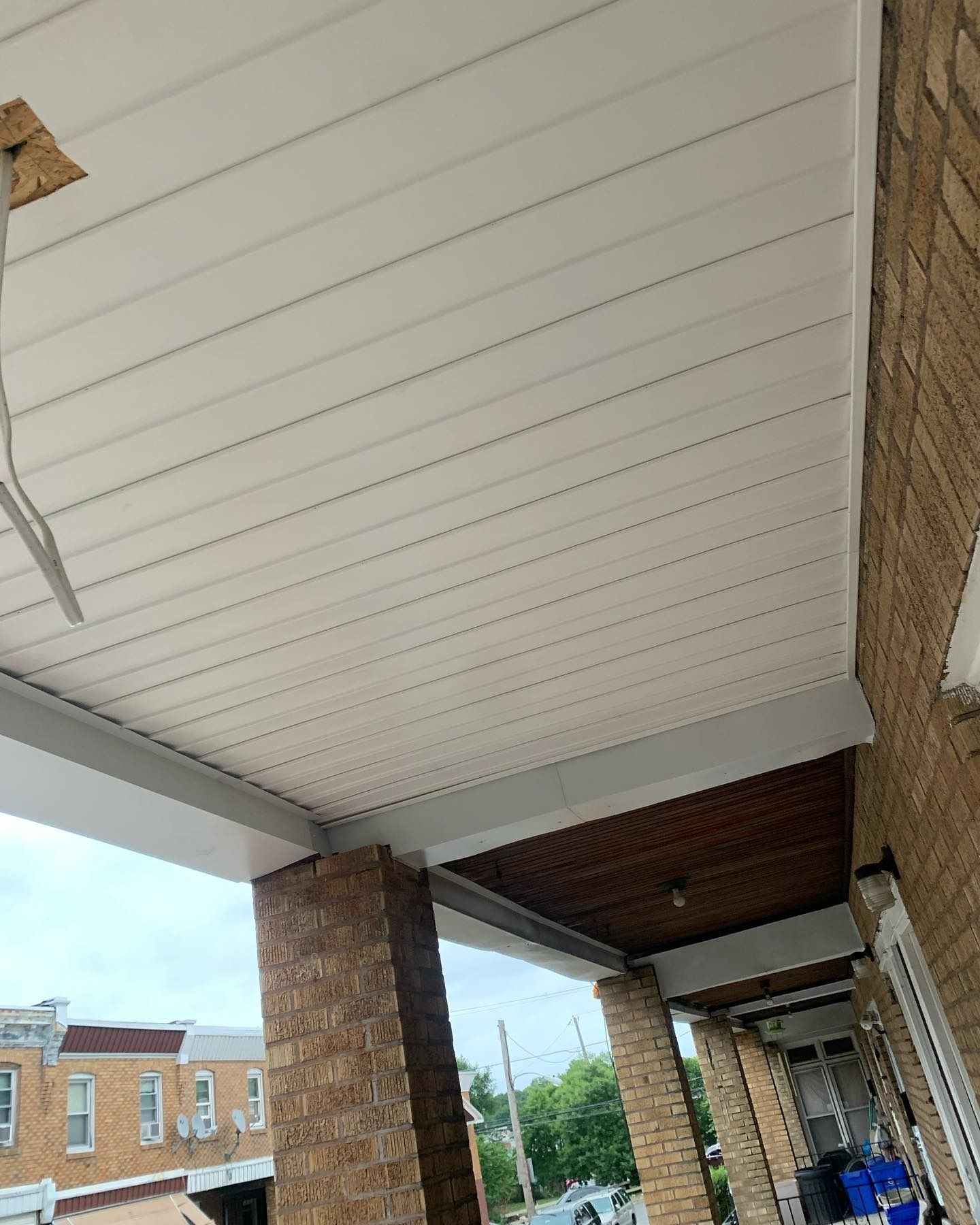Covered brick storefront walkway with white paneled ceiling and blue sky beyond