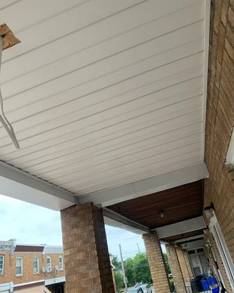 Covered brick storefront walkway with white paneled ceiling and blue sky beyond