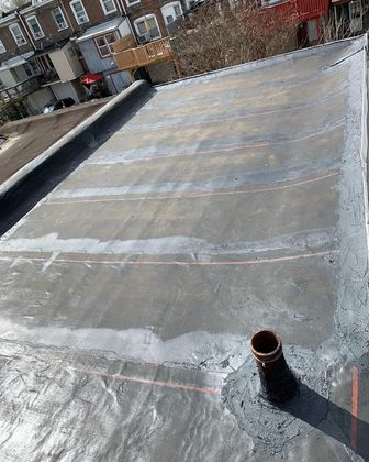 Flat rooftop with reflective roofing membrane and a vent pipe in the foreground.