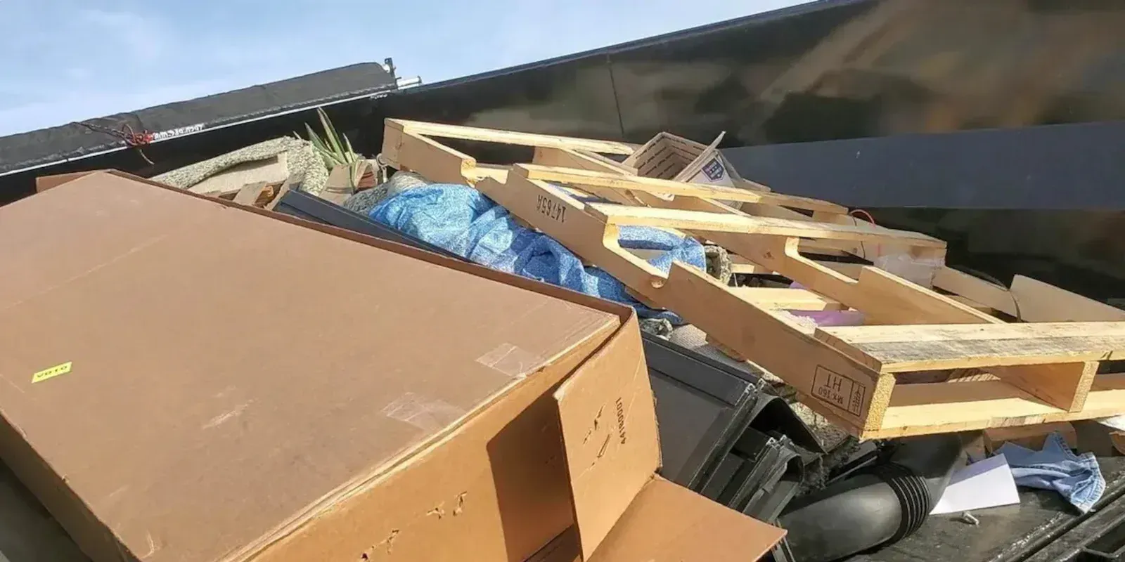 A large cardboard box and a wooden pallet resting in the back of a truck bed. Local dumpsters rental in Pflugerville