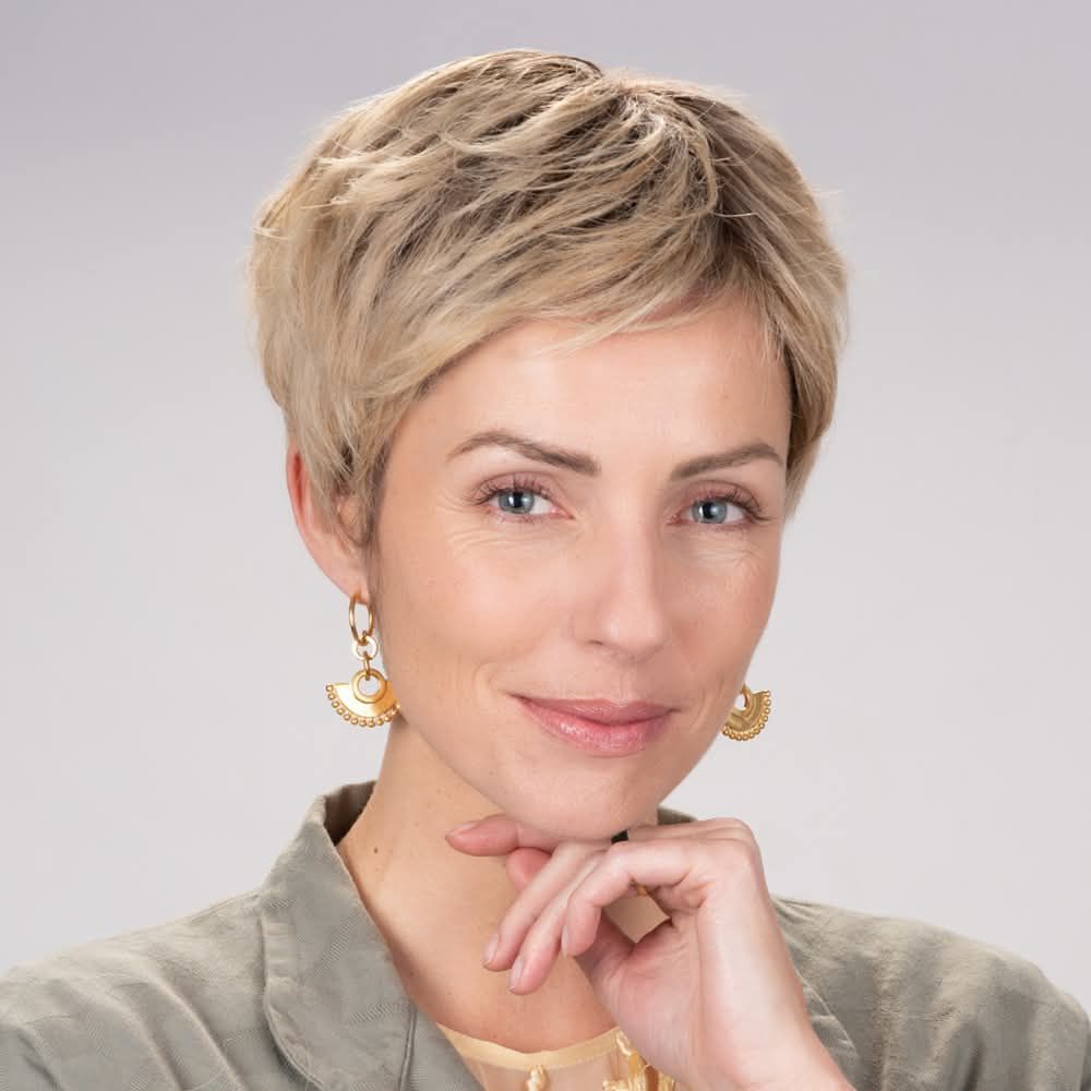 Une femme aux cheveux blonds courts porte des boucles d'oreilles et un collier.